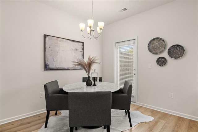 dining area featuring an inviting chandelier, light wood-style flooring, visible vents, and baseboards