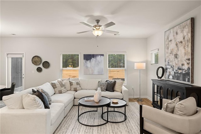 living room featuring wood finished floors, a ceiling fan, and baseboards