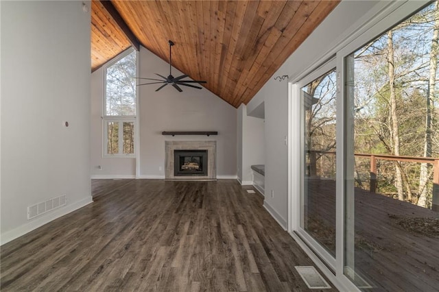 unfurnished living room with ceiling fan, a wealth of natural light, dark wood-type flooring, and a tiled fireplace