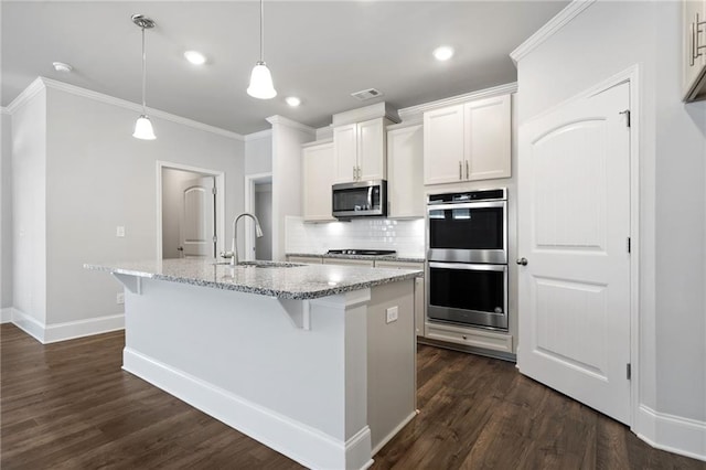 kitchen featuring stainless steel appliances, sink, pendant lighting, white cabinetry, and an island with sink