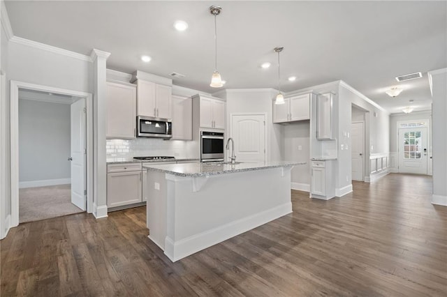 kitchen with white cabinetry, crown molding, decorative light fixtures, a center island with sink, and appliances with stainless steel finishes