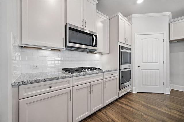 kitchen with decorative backsplash, appliances with stainless steel finishes, light stone counters, dark wood-type flooring, and white cabinets