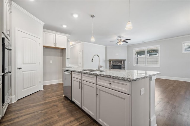 kitchen featuring ceiling fan, sink, light stone countertops, stainless steel dishwasher, and a center island with sink