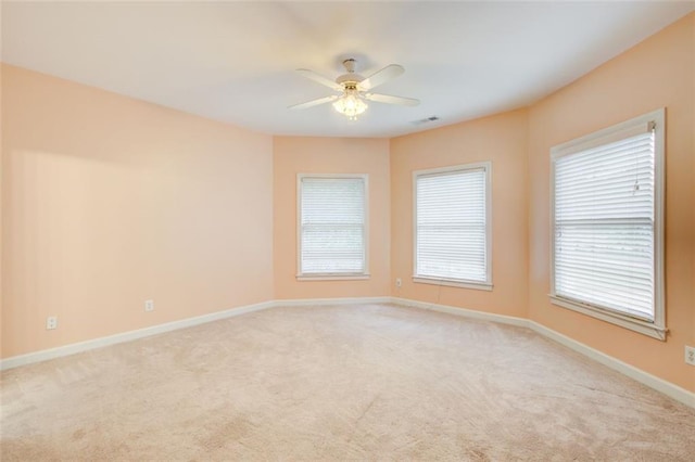 spare room featuring visible vents, a ceiling fan, baseboards, and light carpet