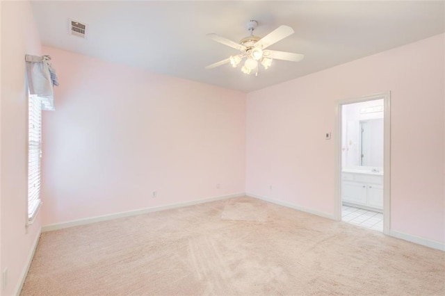 empty room with a ceiling fan, light colored carpet, visible vents, and baseboards