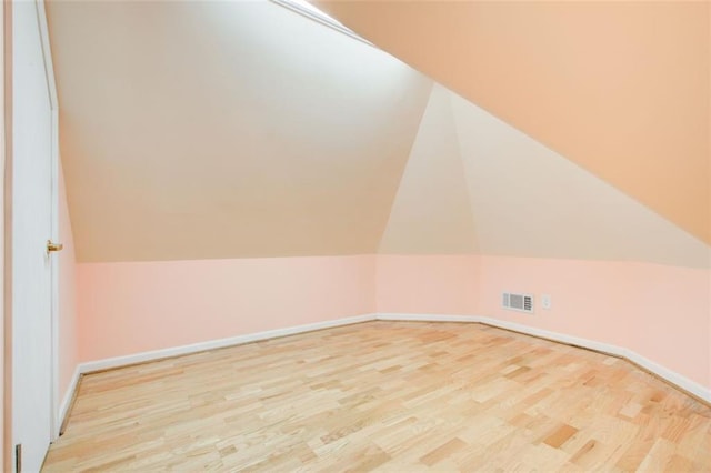 bonus room featuring visible vents, lofted ceiling, baseboards, and wood finished floors