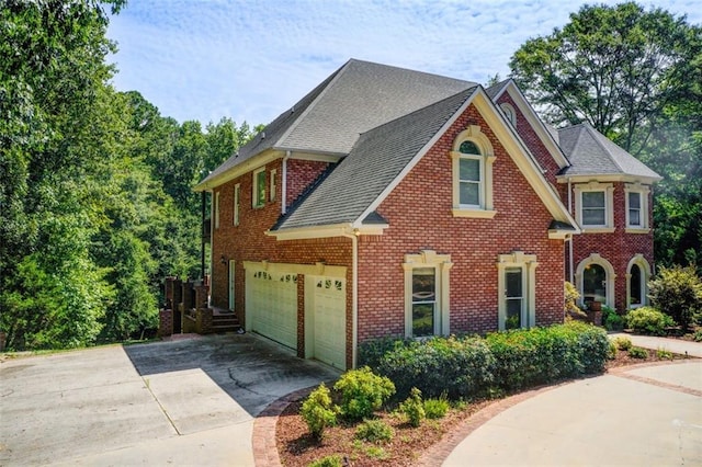 view of front of home with a garage, brick siding, and driveway