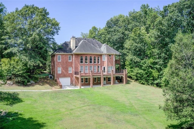 back of property featuring brick siding, a lawn, an attached garage, and a chimney