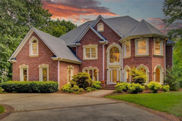 view of front facade featuring a front yard, brick siding, and driveway