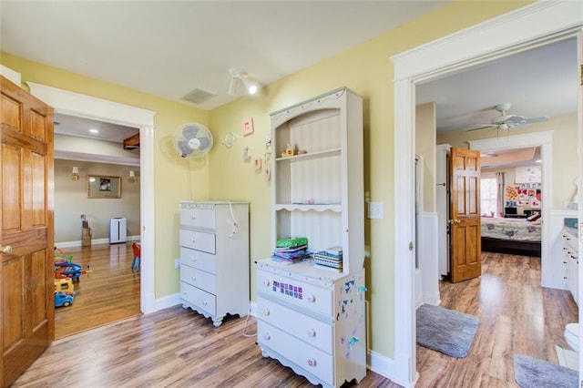 hall featuring baseboards, visible vents, and light wood finished floors