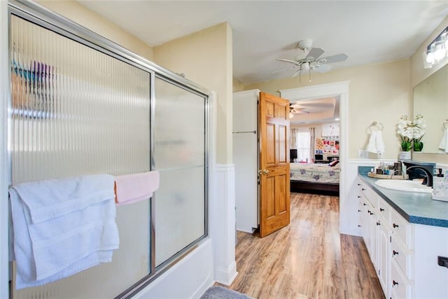 full bathroom featuring vanity, a ceiling fan, wood finished floors, bath / shower combo with glass door, and connected bathroom