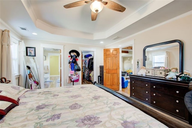 bedroom featuring visible vents, a walk in closet, crown molding, and a raised ceiling