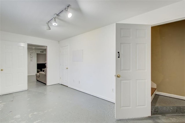 spare room with track lighting and baseboards