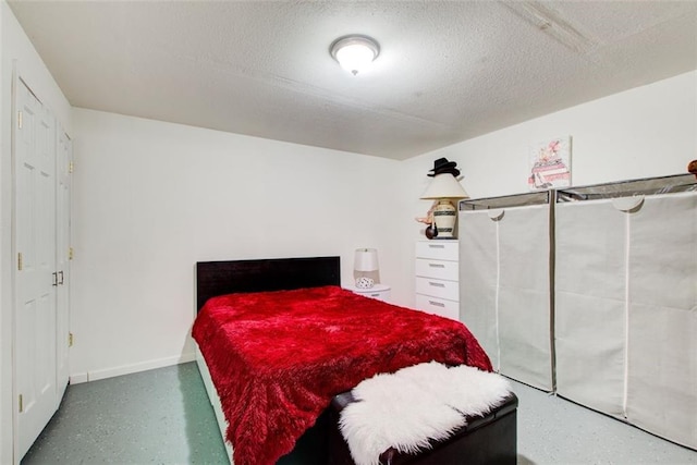 bedroom with speckled floor, baseboards, and a textured ceiling