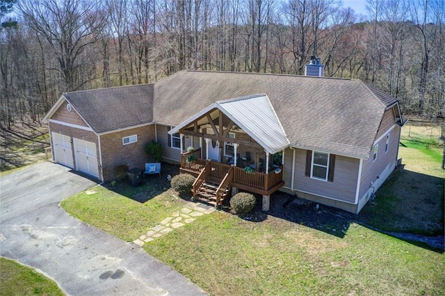 view of front of home featuring a front lawn, an attached garage, a view of trees, and aphalt driveway