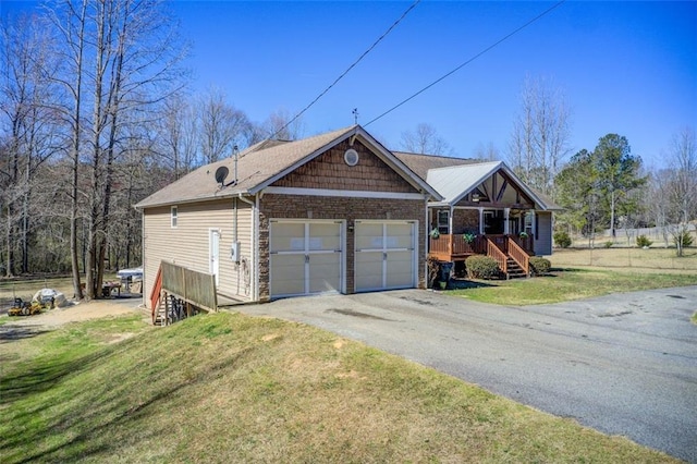 view of front facade featuring stone siding, a garage, driveway, and a front lawn