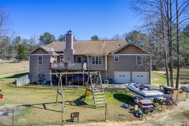 rear view of house featuring a lawn, a chimney, a deck, a garage, and driveway