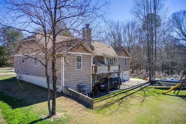 back of house featuring dirt driveway, a wooden deck, a chimney, a yard, and an attached garage