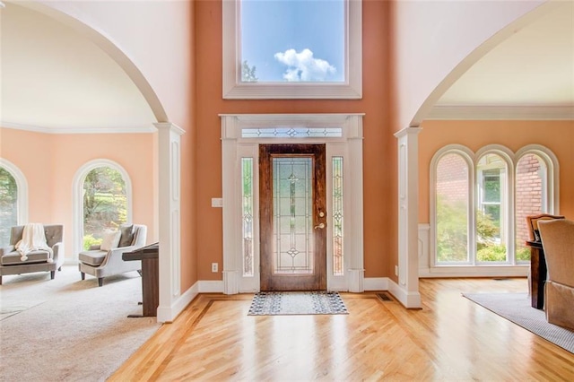 entryway with a wealth of natural light, a high ceiling, crown molding, and baseboards