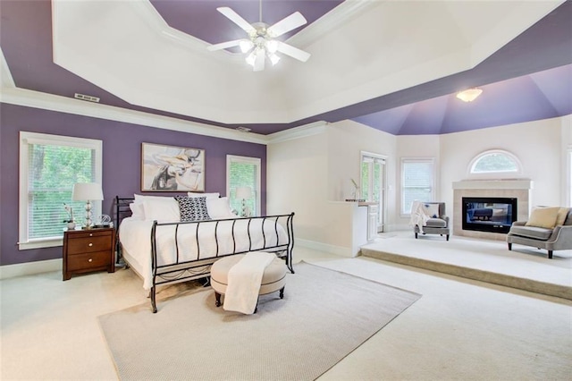 bedroom with carpet flooring, a tile fireplace, baseboards, and a tray ceiling