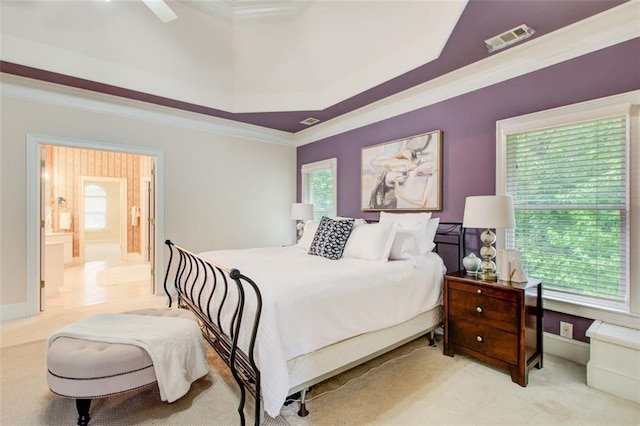 carpeted bedroom with visible vents, ensuite bathroom, baseboards, crown molding, and a raised ceiling