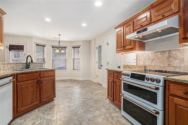 kitchen with pendant lighting, sink, light stone countertops, a healthy amount of sunlight, and white appliances