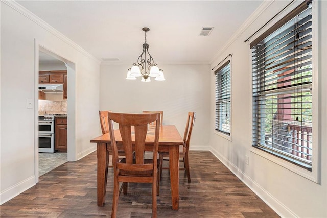 dining room featuring dark hardwood / wood-style flooring, crown molding, and an inviting chandelier