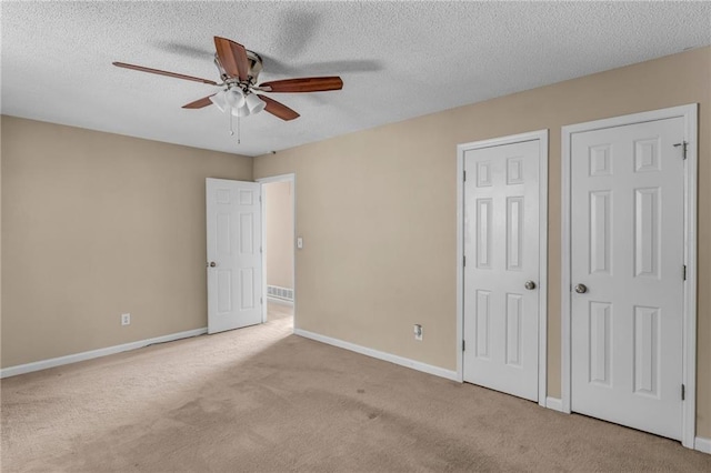 unfurnished bedroom with ceiling fan, a textured ceiling, and light carpet