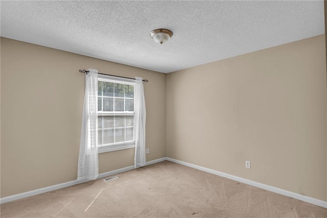 empty room featuring a textured ceiling and light carpet