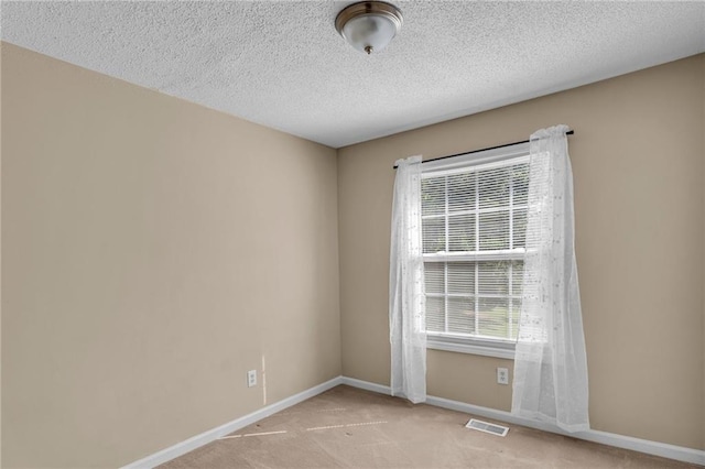 empty room featuring a textured ceiling and light carpet