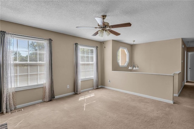 empty room with light carpet, ceiling fan, a textured ceiling, and a healthy amount of sunlight