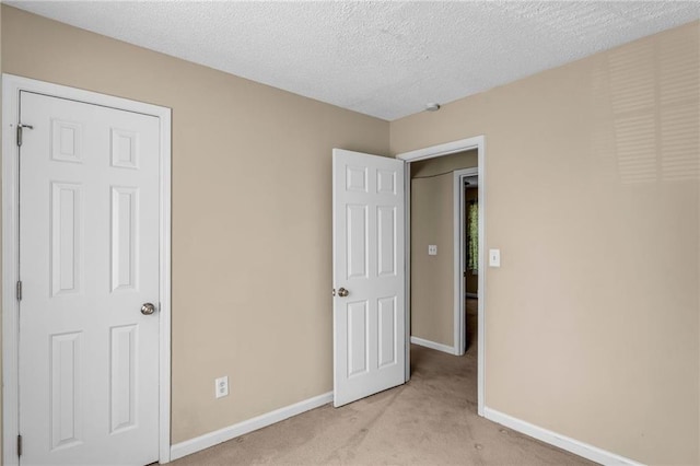 unfurnished bedroom with light carpet and a textured ceiling