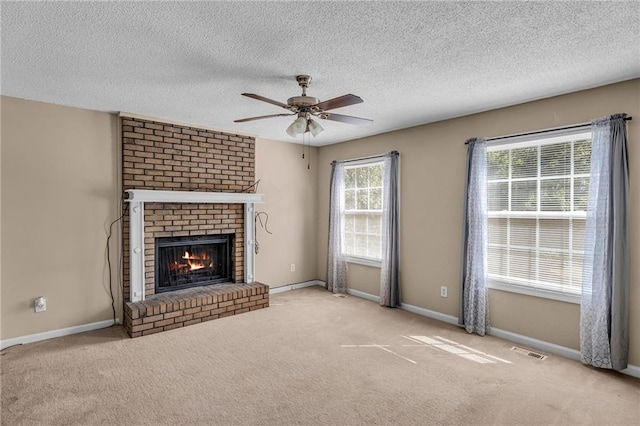 unfurnished living room featuring a brick fireplace, ceiling fan, light carpet, and a textured ceiling