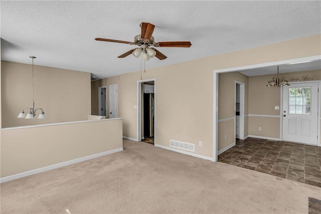 empty room featuring a textured ceiling, ceiling fan with notable chandelier, and dark colored carpet