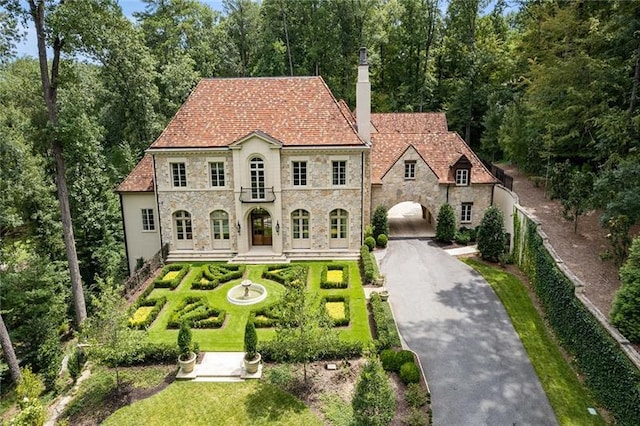 view of front of home featuring stone siding, driveway, and a chimney