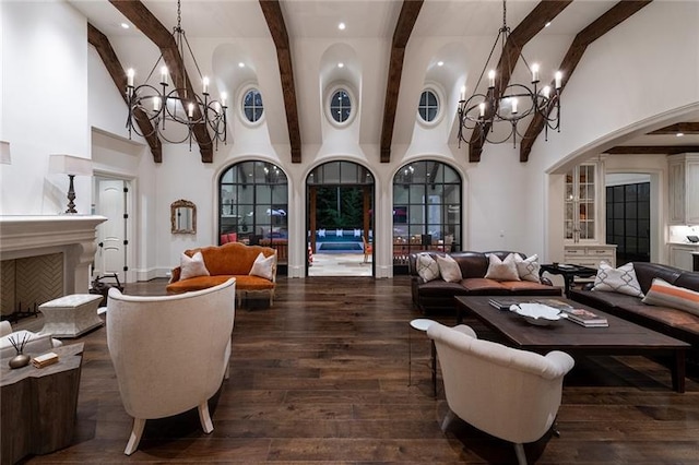 interior space featuring dark wood-style floors, a fireplace, a high ceiling, and an inviting chandelier