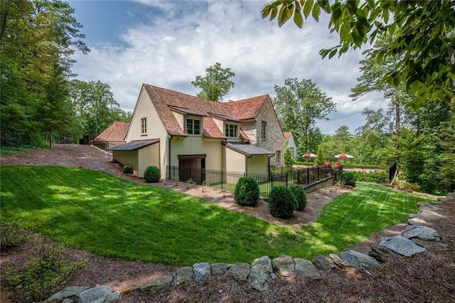 exterior space featuring stone siding, stucco siding, a yard, and fence