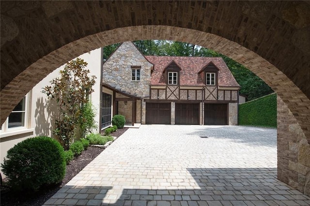 view of front facade with decorative driveway, stone siding, and a garage