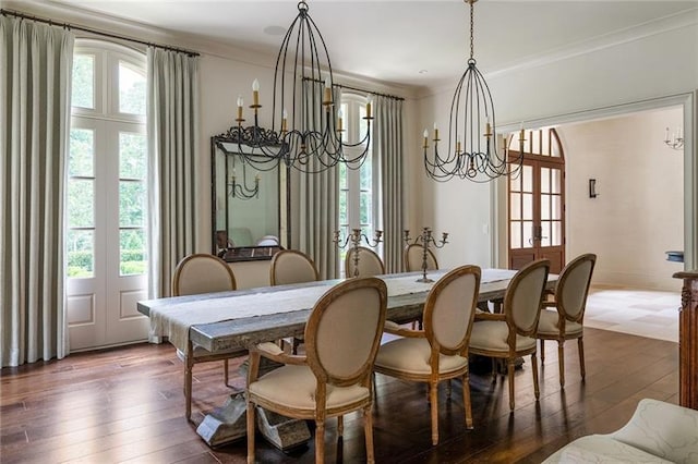 dining space featuring dark wood finished floors, crown molding, french doors, and an inviting chandelier