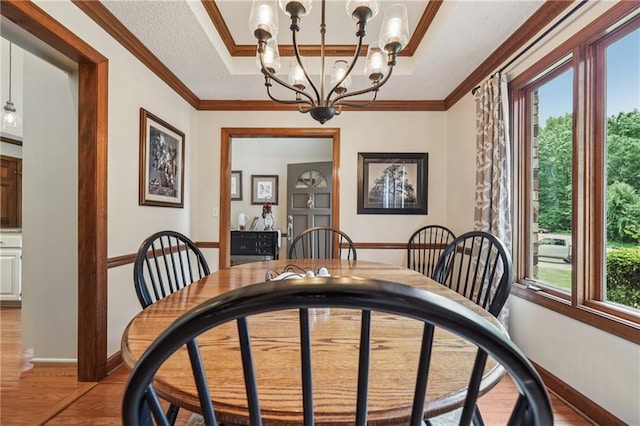 2011 Sturbridge Ln, Buford, GA 30519 - dining room with light wood-style flooring, a chandelier, baseboards, crown molding, and a raised ceiling