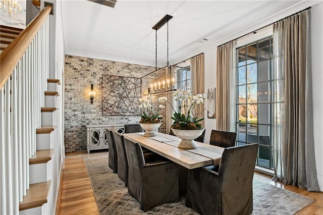 dining space with light hardwood / wood-style floors, a healthy amount of sunlight, crown molding, and a chandelier