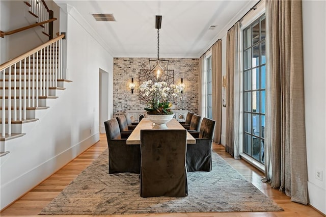 dining area featuring a chandelier, ornamental molding, and light hardwood / wood-style flooring