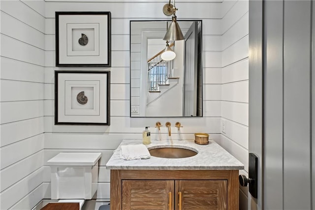 bathroom with wood walls, vanity, and toilet