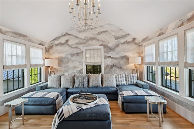 living room featuring hardwood / wood-style flooring, lofted ceiling, and an inviting chandelier