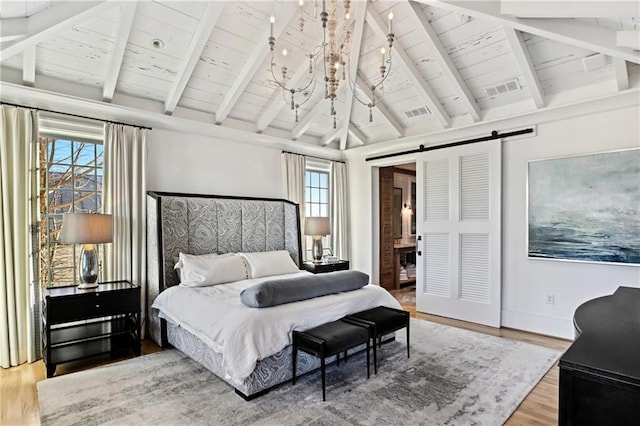 bedroom featuring a barn door, a notable chandelier, multiple windows, and hardwood / wood-style flooring