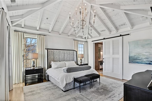 bedroom with a barn door, an inviting chandelier, light hardwood / wood-style flooring, and multiple windows