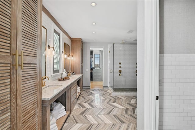 bathroom featuring vanity, a shower with door, and tile walls