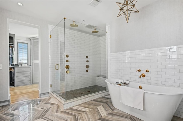 bathroom featuring tile walls and independent shower and bath