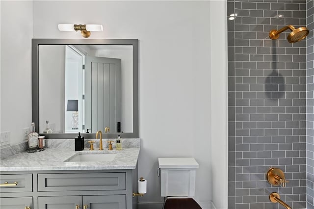 full bathroom with tiled shower / bath, vanity, and toilet