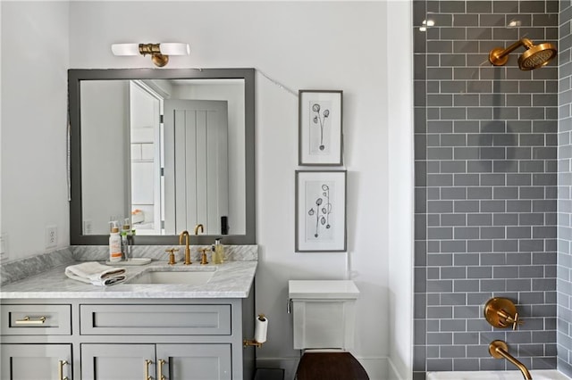 full bathroom featuring tiled shower / bath, vanity, and toilet